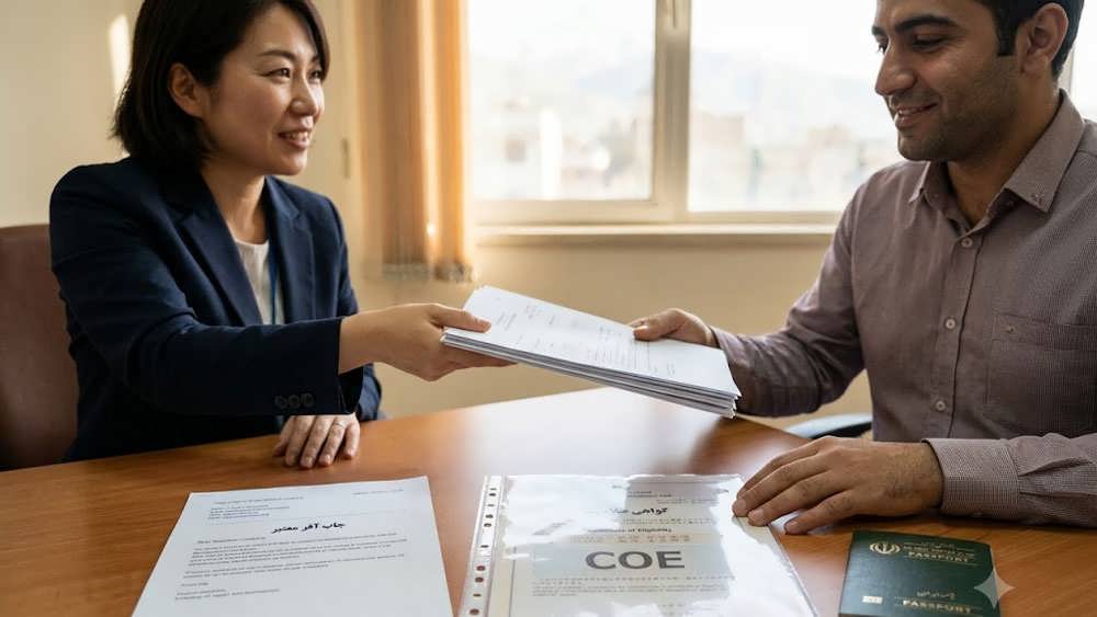 یک نمای نزدیک مستند از دست های متقاضی ایرانی که مدارک خود شامل جاب آفر و گواهی COE (Certificate of Eligibility) ژاپن و پاسپورت ایرانی را به افسر سفارت در تهران تحویل می دهد.